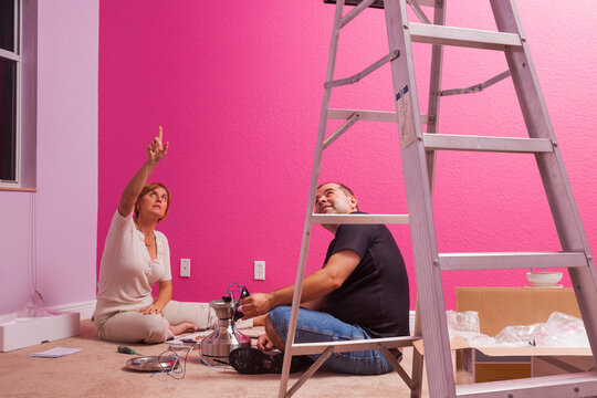 Man And Woman Preparing For Installation Of A Ceiling Fan In A Bedroom In The House