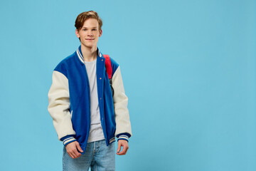 Fototapeta premium horizontal portrait of a handsome, joyful student guy with a red backpack on his shoulder, looking at the camera