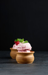 Pink scoops of popsicles with red currants on a black table. Ice cream