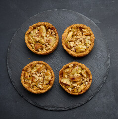 Fruit mini tart with apples on a black round graphite board, top view