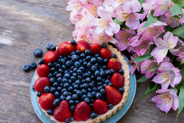 Cake with blueberries and strawberries and flowers. Sweets and flowers.