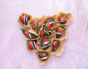 strawberries covered with chocolate on pink background