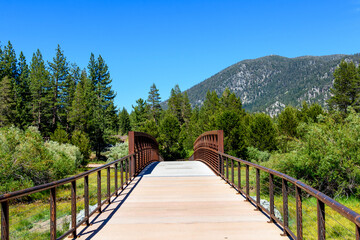 Fototapeta premium Elevated boardwalk leads to prefabricated small steel bridge over the floodplain of Trout Creek Meadow at South Lake Tahoe, California