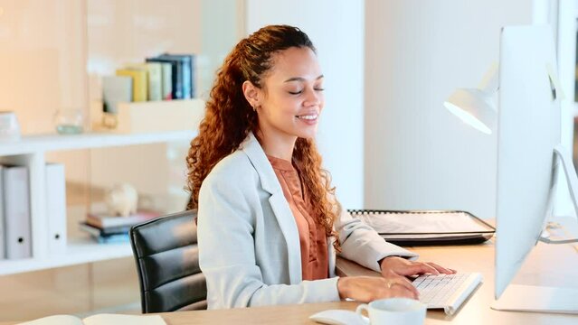 Doing research and planning in a startup company. Young business woman working on a computer in an office. Confident and happy entrepreneur smiling while typing emails and compiling online reports.