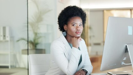 A serious black business woman looking focused while working on computer in a modern office. Confident young professional feeling ambitious and motivated for success in a startup company
