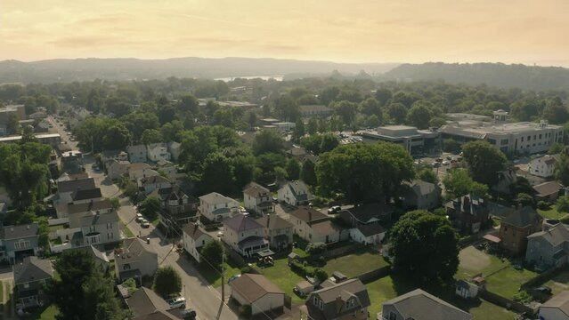 A slow forward summer evening or morning aerial establishing shot of a small Pennsylvanian town. The Ohio River in the distance.  	