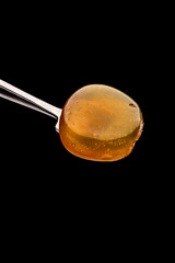 A fresh, opaque coin of Rosin on a titanium dab tool with a black background. 