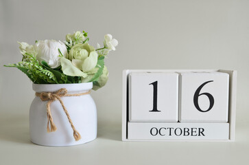 October 16, Cover natural background, white wooden Calendar cube with a pot flower on white...