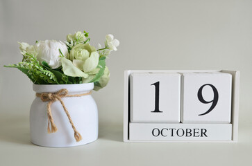 October 19, Cover natural background, white wooden Calendar cube with a pot flower on white...