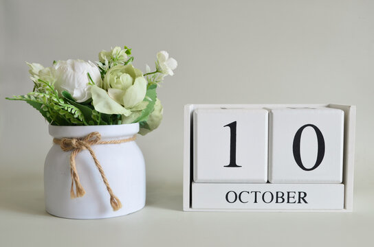 October 10, Cover natural background, white wooden Calendar cube with a pot flower on white background.