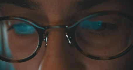 Cinematic close up of woman eyes with reading glasses while using laptop.