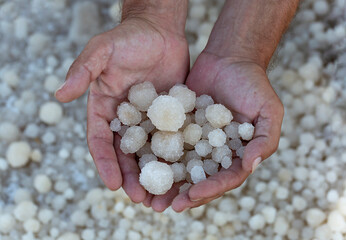 Crystallised Dead Sea-salt of men palms. Male hands with pile salt crystals. Blurred background of Dead Sea shore surface. Extraction of salt by hand. Useful minerals.Treatment of jordanian salt.