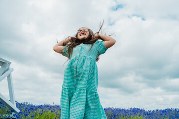 A happy girl in a mint dress jumps up.Little kid in a lavender field, running and jumping, and has fun.Happy smiling daughter enjoying vacation in flower field