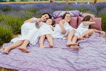 Cheerful family lying on the bed.Happy family resting in summer park.Beautiful field of blue violet...