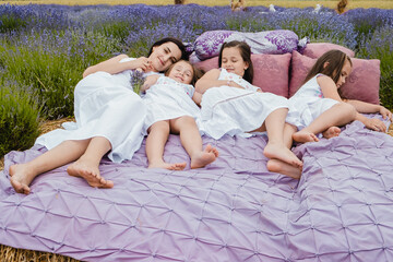 Cheerful family lying on the bed.Happy family resting in summer park.Beautiful field of blue violet...