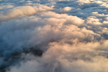 Aerial view from above at high altitude of dense puffy cumulus clouds flying in evening. Amazing...