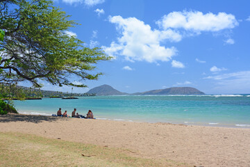 Fototapeta na wymiar Family relaxing under a tree on Kahala beach in Honolulu on the island of Oahu in Hawaii. 