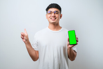 Young handsome asian man showing blank screen of smartphone very happy pointing with hand and finger to the side