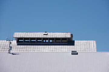 Modern rural warehouse roof with communication antennas under blue sky