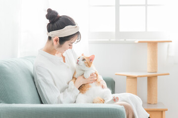 家で猫を抱っこする日本人女性（ペット・飼い主・キャットタワー）

