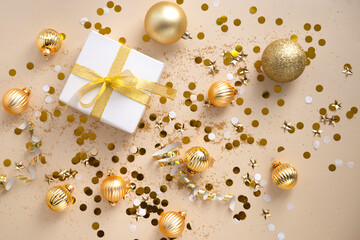new year decorations golden color with confetti and gift box on beige color background