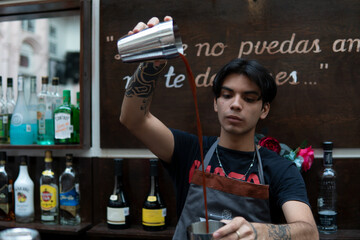 Latin bartender mixing a drink in an impressive way. Cocktail skills of a Hispanic waiter at the bar counter. Barman mixing the liquids doing impressive tricks.