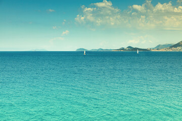 Sea landscape, two sailboats in the background of the island, the city of Dubrovnik on the horizon