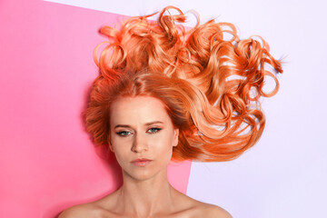 Beautiful woman with long orange hair on color background, top view