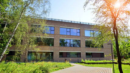 Modern office building stands among lush green trees.