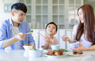 little boy  enjoy eating food with father and mother. Happy Asian  family having dinner at home