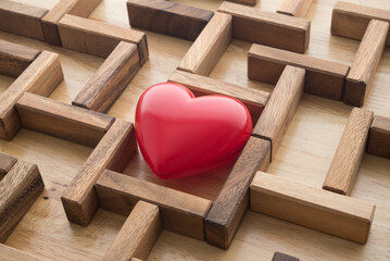 Abstract red heart can't find a way out in middle of wooden maze background. Problems of mental...
