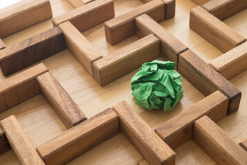 Green crumpled paper find escape exit in wooden maze background. Business strategy planning for...