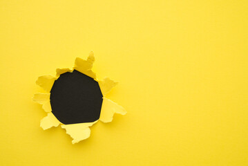 Flat lay of yellow paper breakthrough with black hole background copy space. Design decoration,...