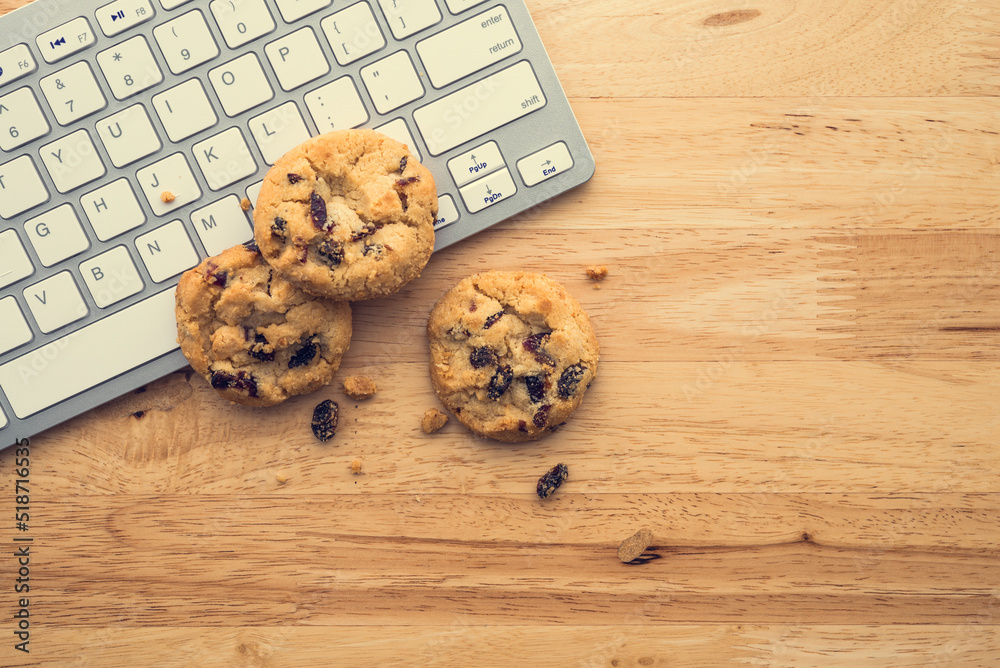 Wall mural flat lay of white chocolate chip cookies on keyboard computer on wooden table background copy space.