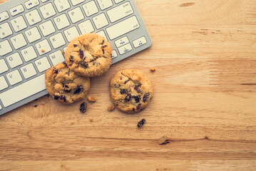 Flat lay of white chocolate chip cookies on keyboard computer on wooden table background copy space. Cookies website internet homepage policy accpeted or blocks concept. - obrazy, fototapety, plakaty
