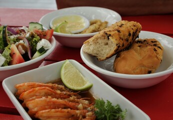 Food on a table - shrimps with lemon, vegetable salad and bread