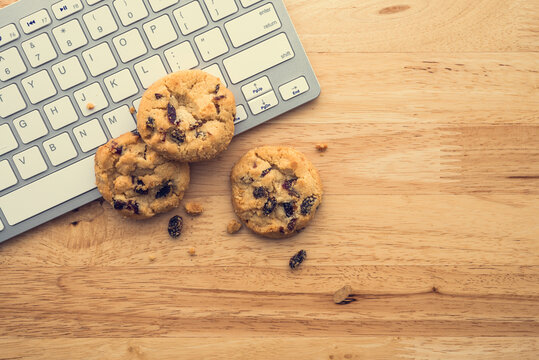 Flat lay of white chocolate chip cookies on keyboard computer on wooden table background copy space. Cookies website internet homepage policy accpeted or blocks concept.