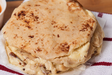 Pupusas on a wooden board with curtido and sauce over a black marble background