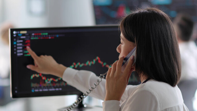 Close up of African-American female broker talk on phone pointing at computer screen with charts - Powered by Adobe
