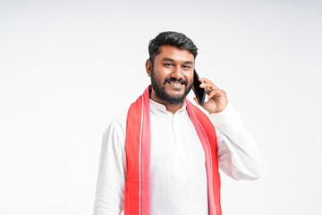 Young indian farmer talking on mobile phone over white background.