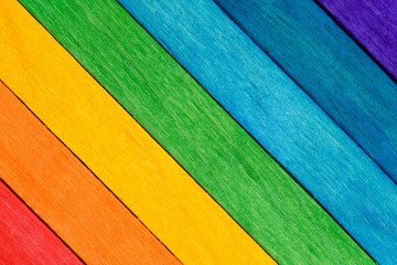 Close-up of a painted rainbow wooden wall. Fun background for kids decor and design. Multi-colored bright wooden boards are arranged diagonally. Selective focus.