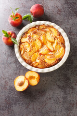 Homemade peach cobbler crumble in baking dish over concrete gray background. Vertical top view from...