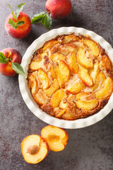 Close up of fresh organic peaches and delicious peach Cobbler baked in a ceramic dish on the table. Vertical top view from above