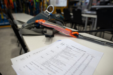 Harness inspection checklist paper placing on the table, defocused harness, shock absorber lanyards...