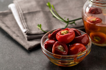 Red chilli stuffed with ricotta and capers in oil, restaurant serving, close-up, gray background