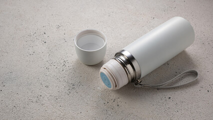 White thermos for drinks for travel and sports on light background, empty place for inscription