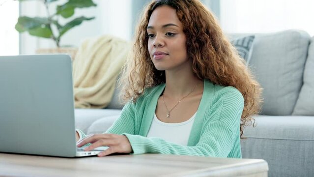 Remote worker using a laptop while sitting in the living room at home looking comfortable. Focused female freelance journalist or volunteer typing an article and writing emails at home in her lounge