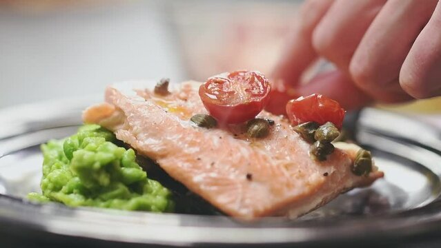Chef serves baked rainbow trout fillet.

