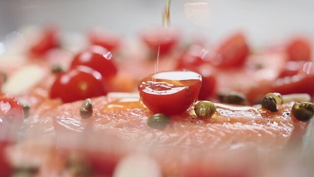 Pouring olive oil over pieces of raw rainbow trout fillet, slow motion.
