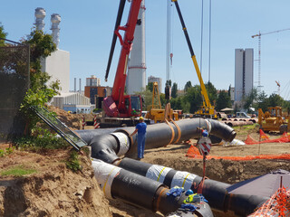 Laying heating pipes in a trench at construction site.